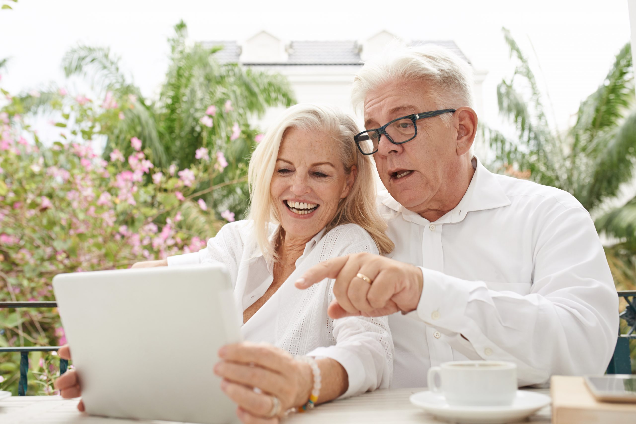 Cheerful aged couple watching videos or reading news on tablet computer